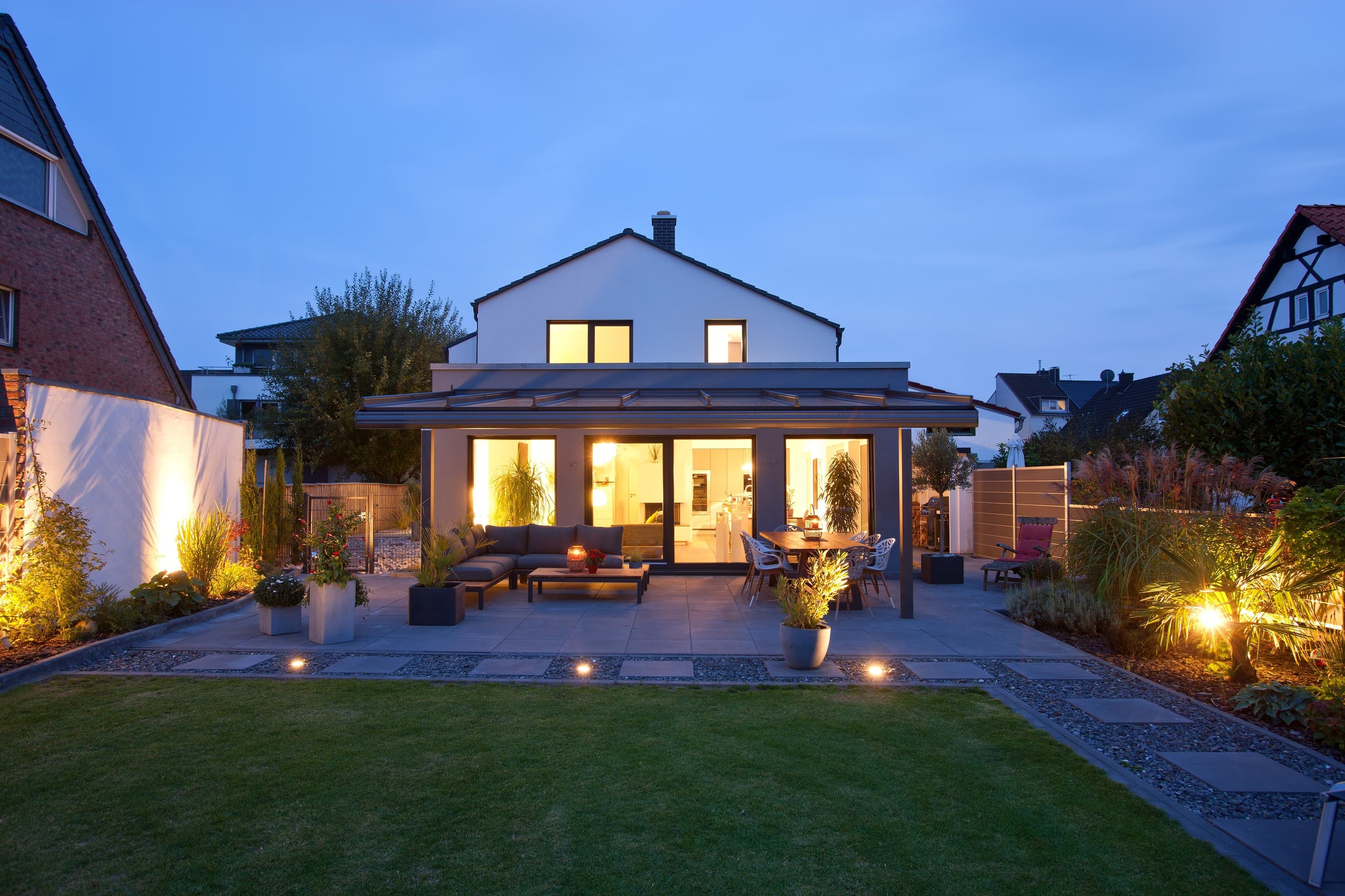 Gefördertes Wohnhaus zur Abenddämmerung mit beleuchtetem Patio